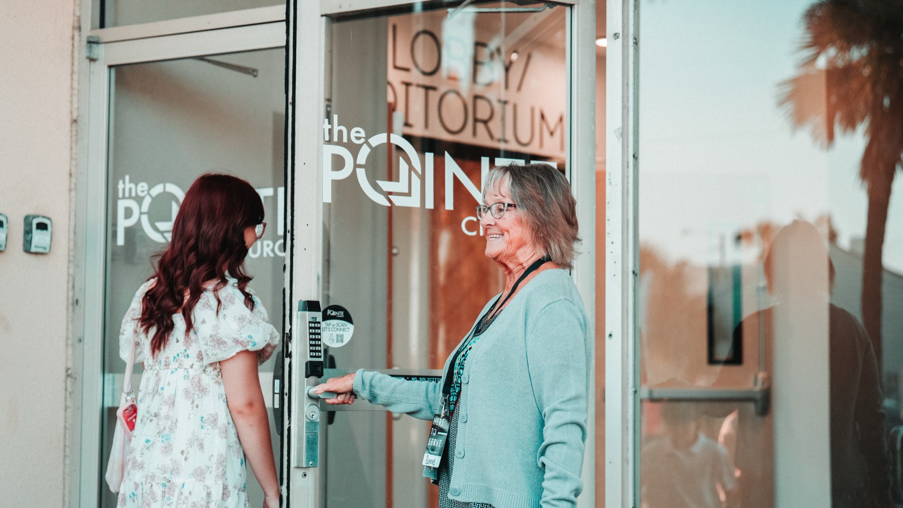 A greeter opening the door for a guest at The Pointe Church