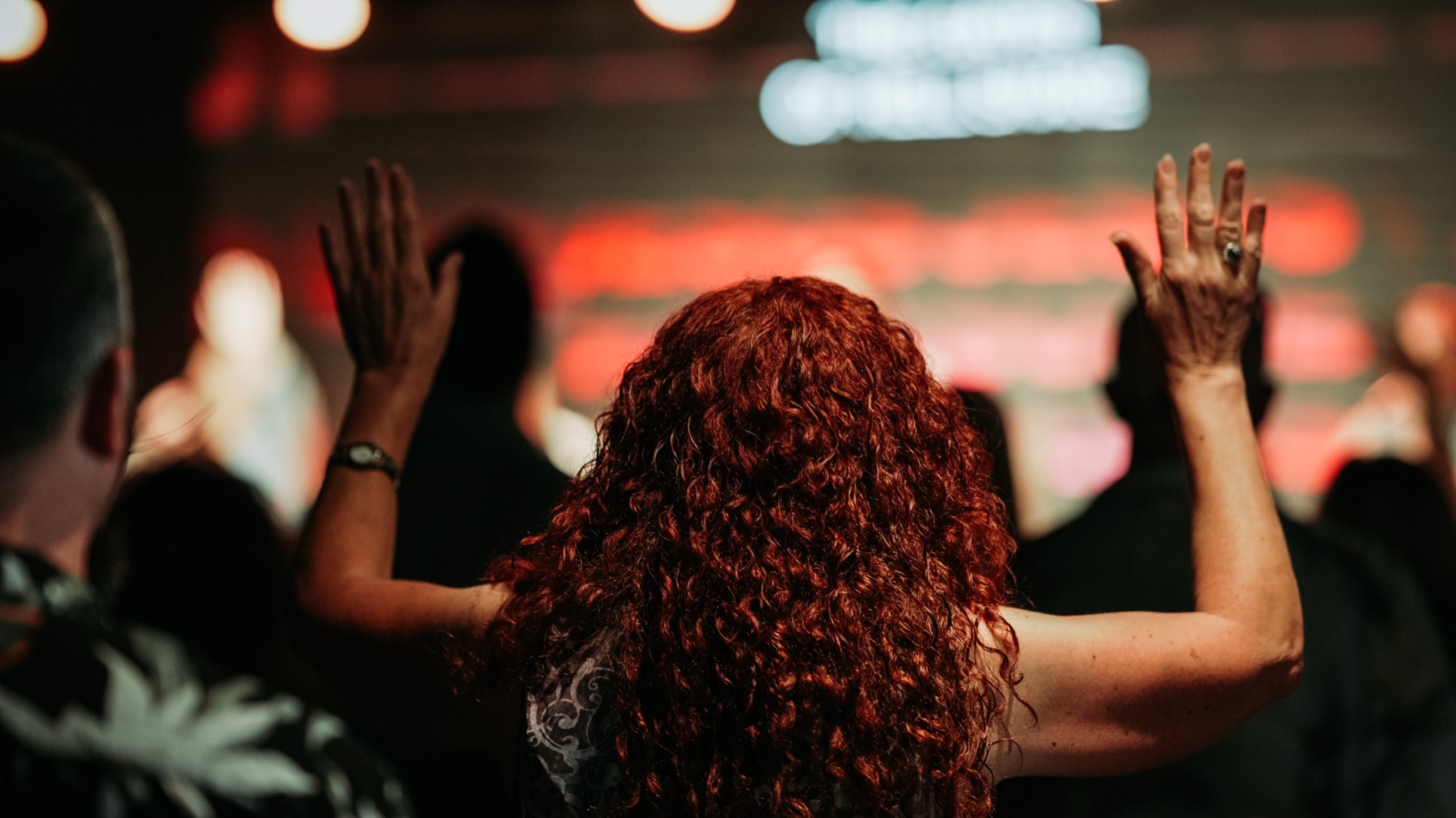 People worshipping with hands raised during a service at The Pointe Church